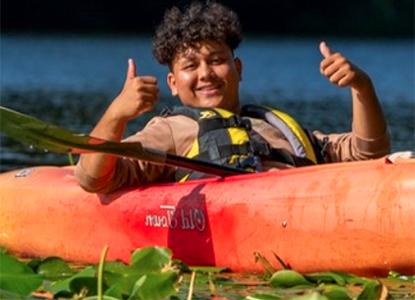 365足彩外围 student in kayak smiling with thumbs up